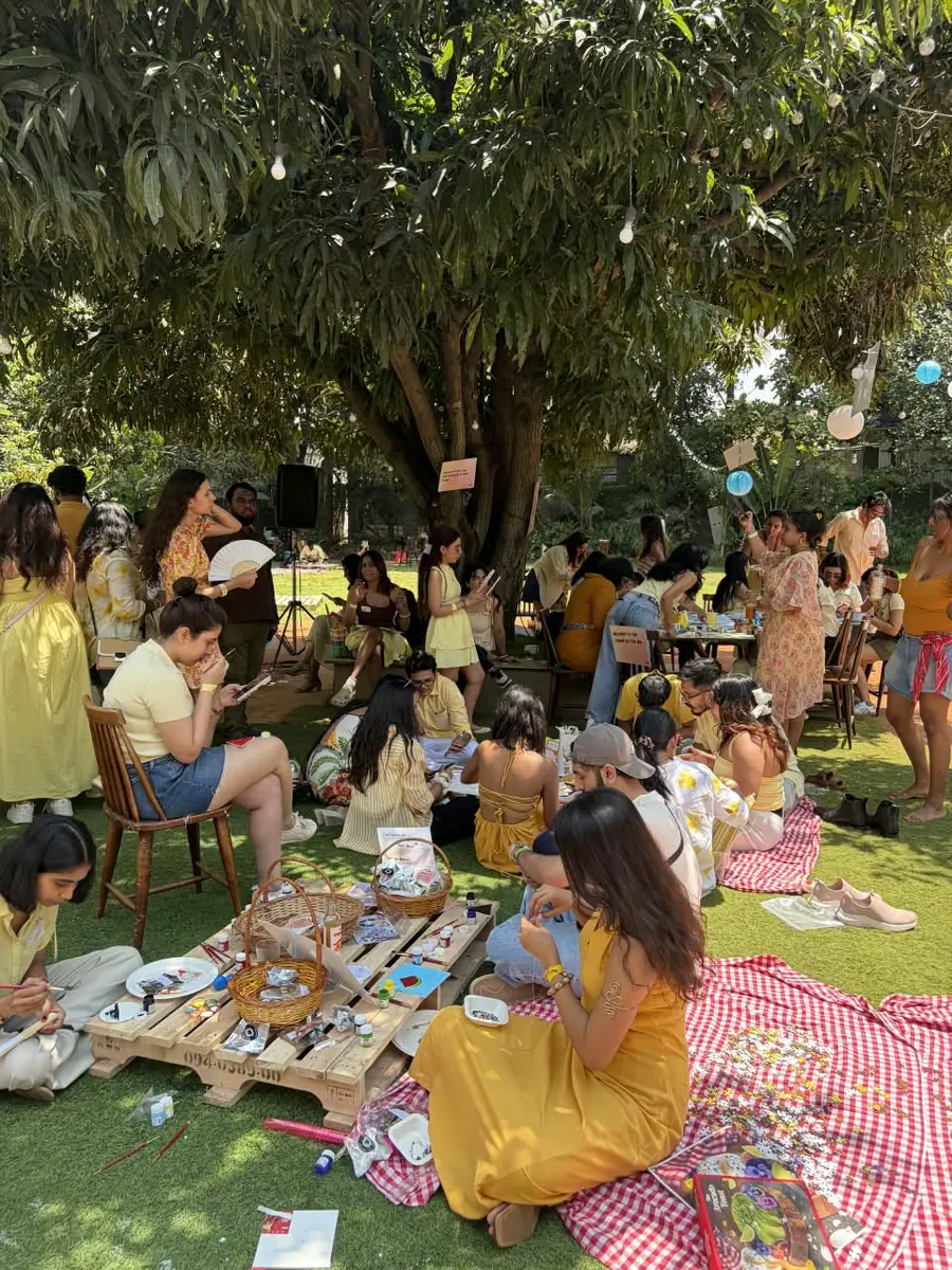 Guests in yellow on picnic blankets under a tree at the Picnic Rave in Bengaluru